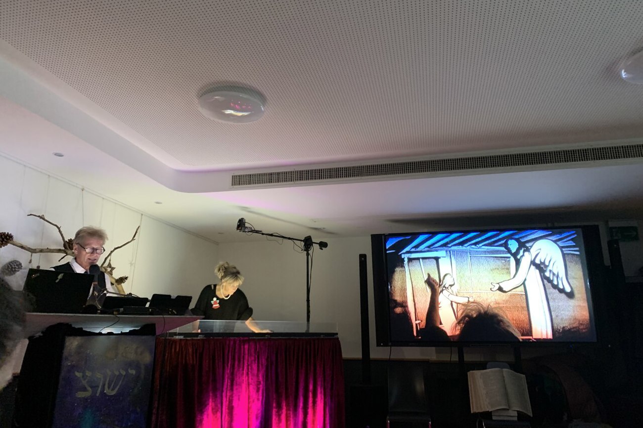 Mit den Fingern malt Claudia Kündig, Bichelsee TG, die Weihnachtsgeschichte in den Sand. Das entstehende Bild wird daneben live projiziert. Foto: Martina Seger-Bertschi
