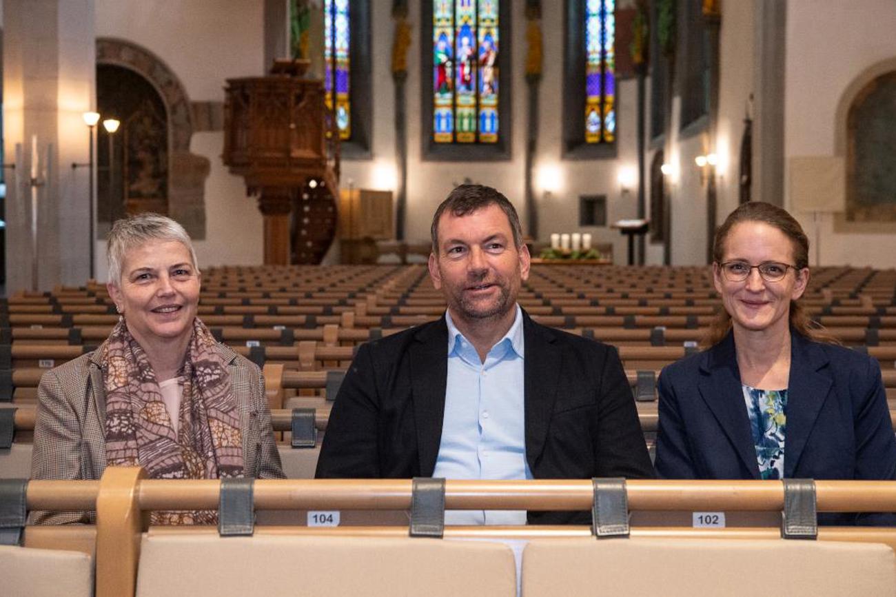 Pfarrerin Verena Hubmann (links) Pfarrer Roland Diethlem und Pfarrerin Ute Nürnberg (rechts) in den Kirchenbänken vom St. Johann nach ihrer Wahl an der Kirchgemeindeversammlung vom 4. November. | Peter Leutert