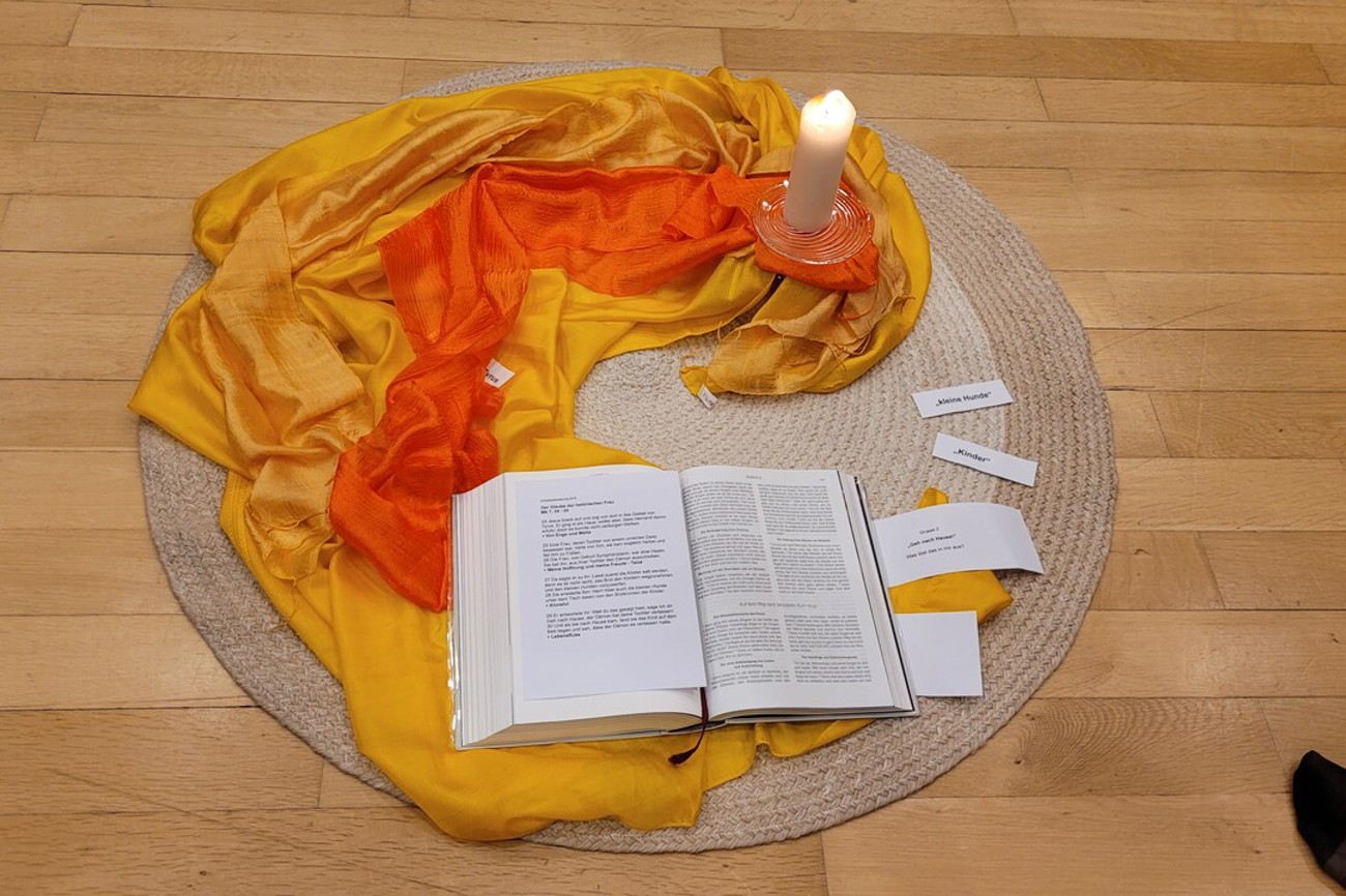 Im Zentrum sind eine Kerze, zwei Tücher, die wie eine Flamme das Licht in den Kreis hinaustragen, und eine Bibel. Foto: sd