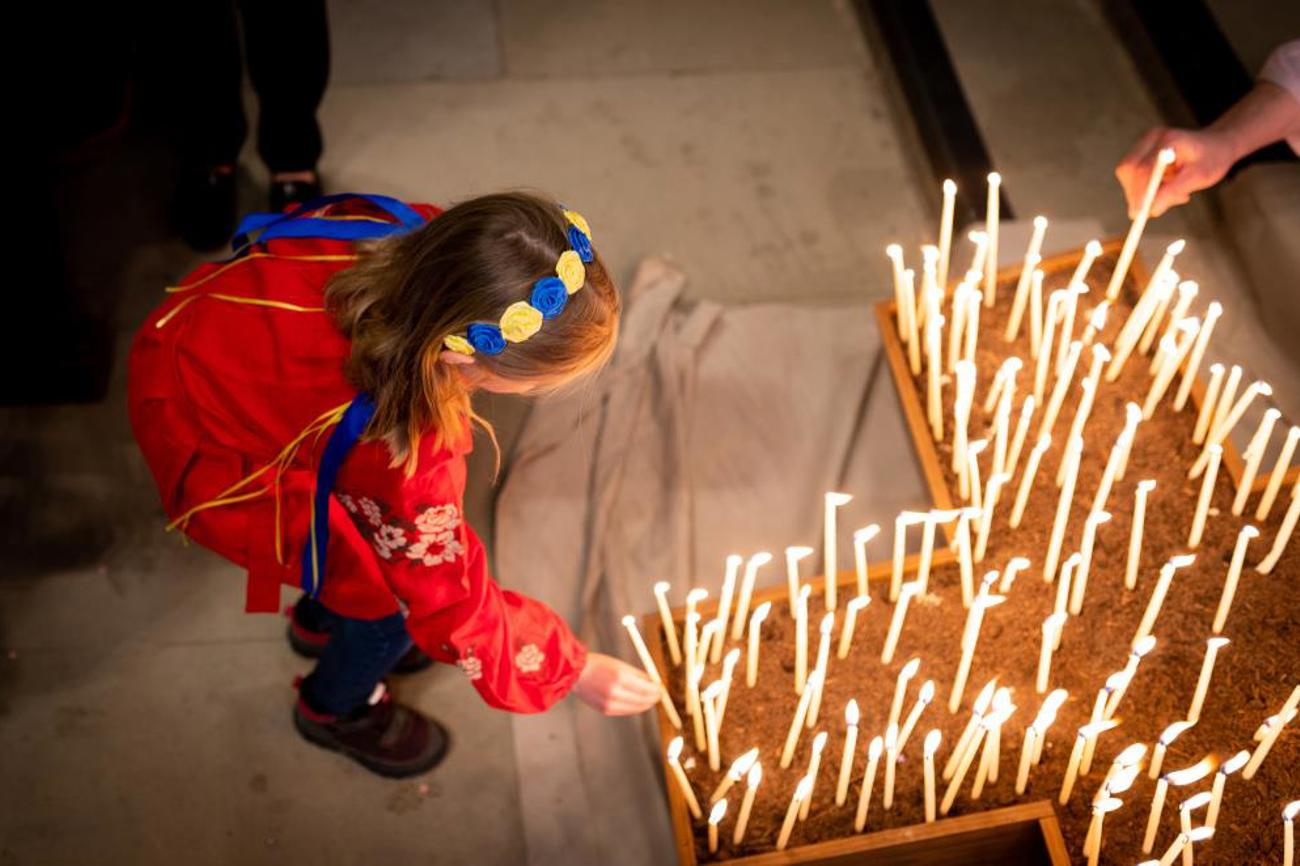 Ein Mädchen aus der Ukraine zündet am ökumenischen Friedensgebet im Berner Münster eine Kerze an.