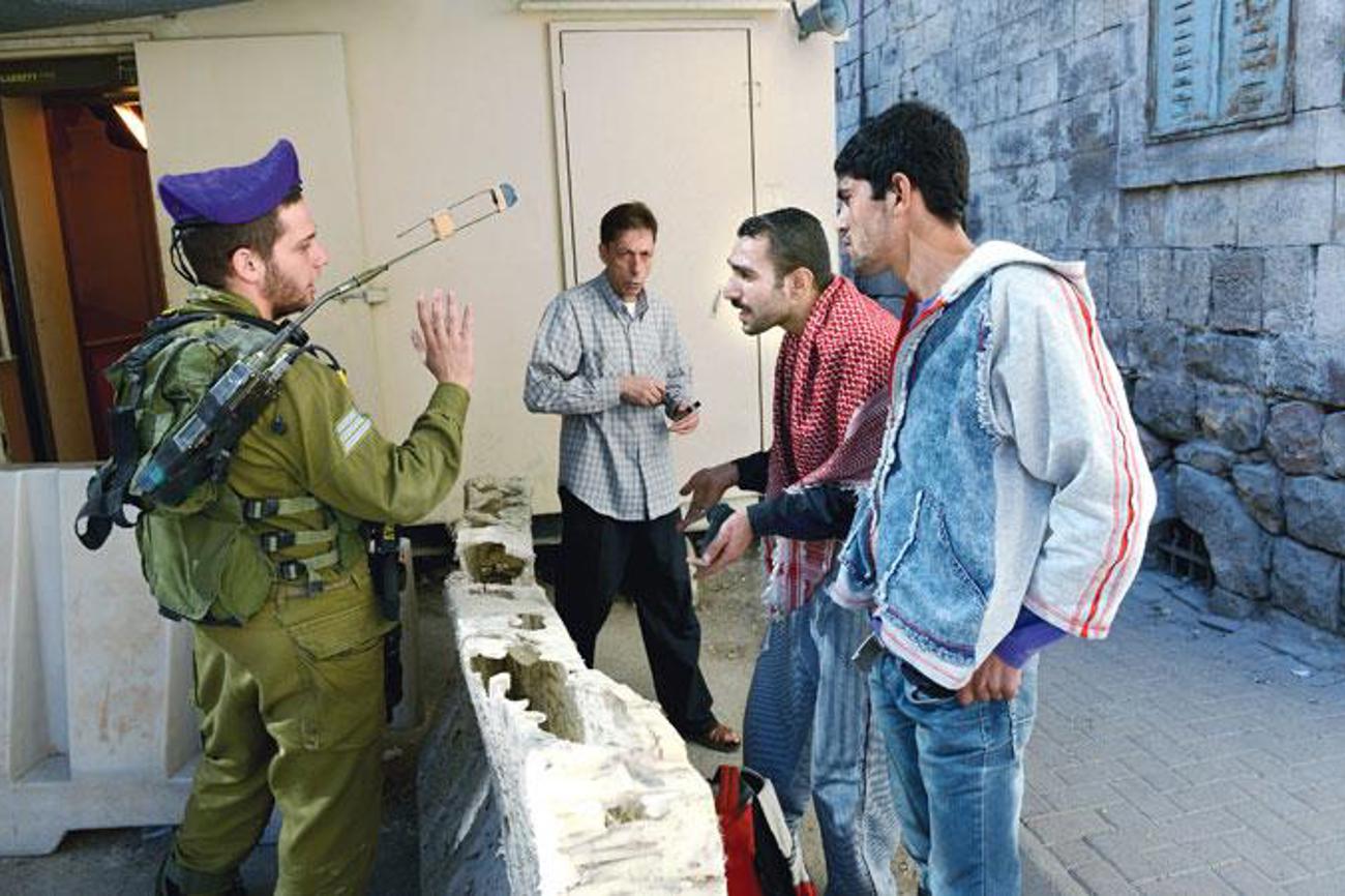 Gibt es Hoffnung auf Annäherung? Ein israelischer Soldat diskutiert an einem Kontrollpunkt in Hebron mit festgenommenen Palästinensern.|EPD-Bild