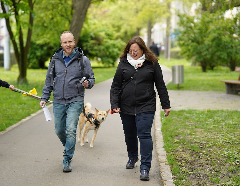 Monika Widmer und Micheal Schäppi im Park zwischen Bahnhof und Aeschenplatz. Ein neugieriger Hund läuft ihnen hinterher.